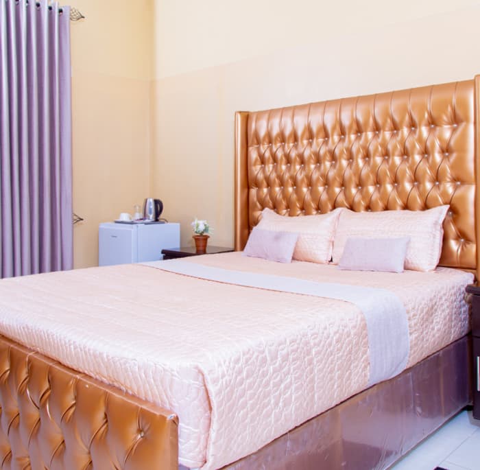 Cosy double room with a tufted headboard and soft, layered bedding.