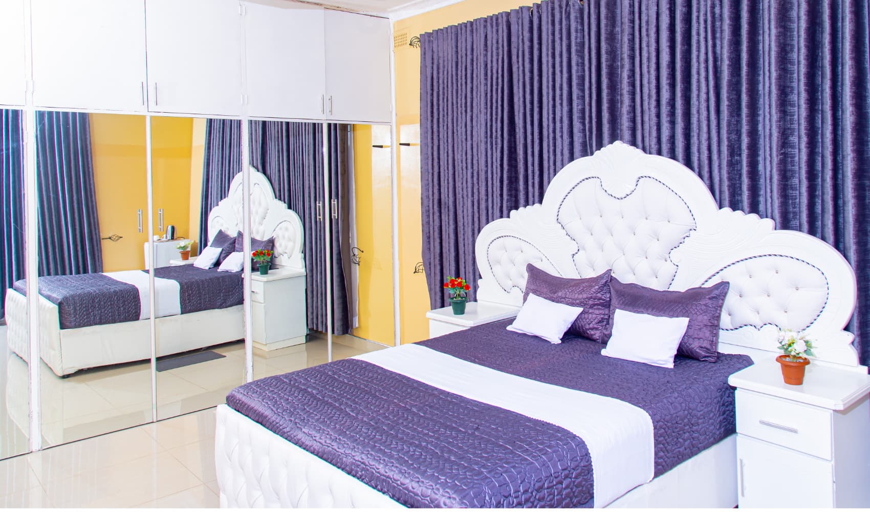 A bright, spacious room at Kwekwe Rose Gardens Guest House with a tufted headboard and mirrored wardrobe.